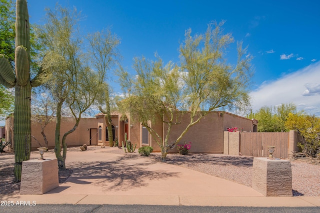 pueblo revival-style home with fence and stucco siding