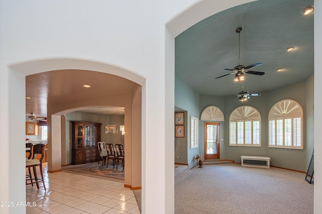 entryway with plenty of natural light, arched walkways, ceiling fan, and light tile patterned flooring