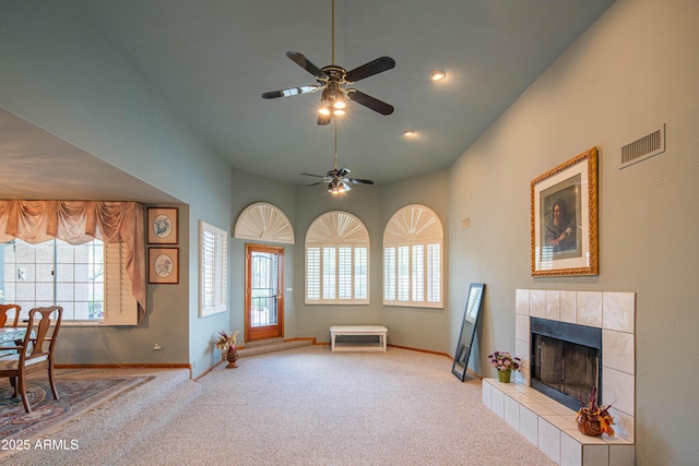 living area with carpet flooring, ceiling fan, visible vents, and a tile fireplace