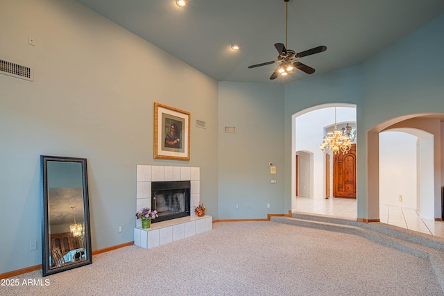 unfurnished living room with high vaulted ceiling, light carpet, arched walkways, and visible vents