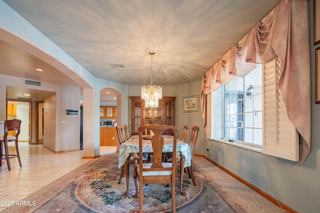 dining area with arched walkways, baseboards, visible vents, and an inviting chandelier