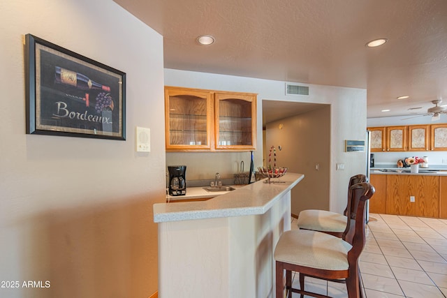 kitchen featuring recessed lighting, a sink, visible vents, and glass insert cabinets