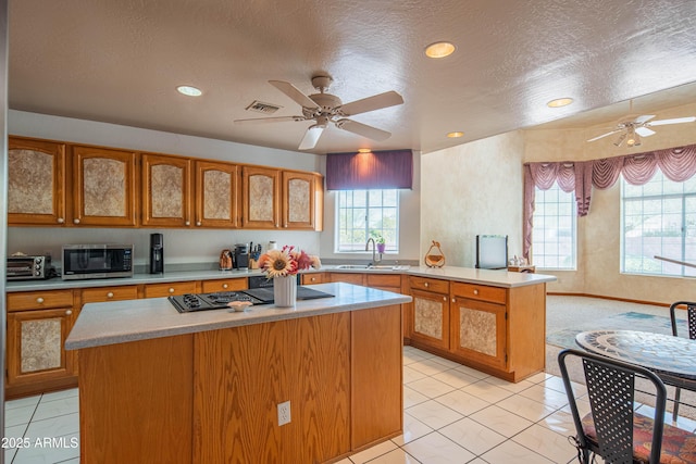kitchen with stainless steel microwave, ceiling fan, a sink, and stovetop with downdraft