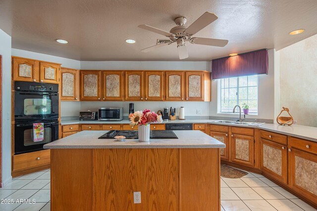 kitchen with a center island, a sink, a toaster, light countertops, and black appliances