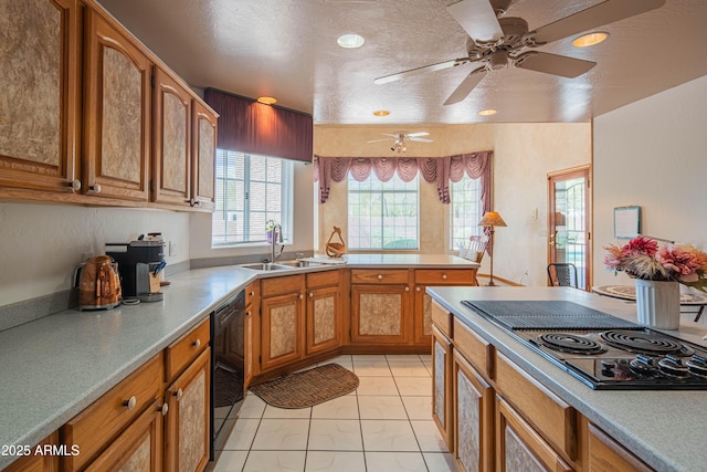 kitchen featuring a sink, a peninsula, black appliances, and brown cabinets