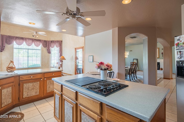 kitchen featuring a ceiling fan, arched walkways, light tile patterned floors, and black electric stovetop