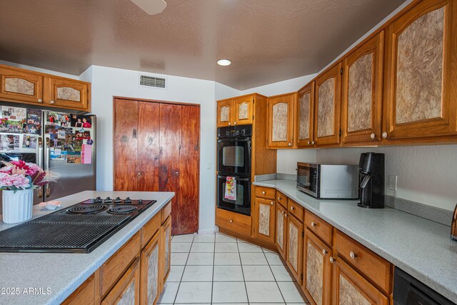 kitchen with visible vents, brown cabinetry, black appliances, and light countertops