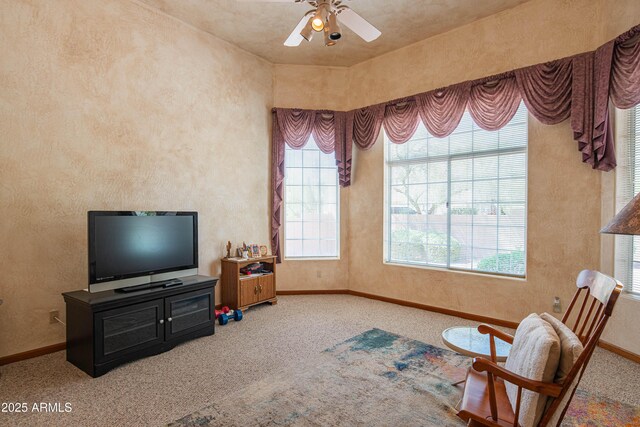 living area with carpet floors, a ceiling fan, baseboards, and a textured wall