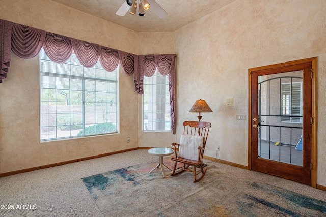 living area with baseboards, carpet flooring, and a ceiling fan