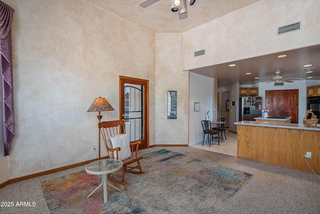 interior space with ceiling fan, visible vents, light carpet, and baseboards