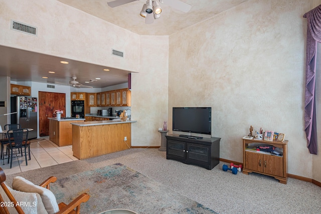 living area featuring visible vents, a ceiling fan, and light colored carpet