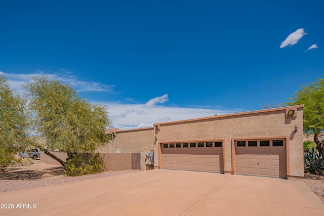 pueblo revival-style home with an attached garage, stucco siding, and concrete driveway