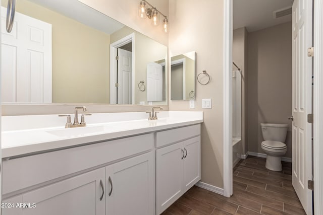 full bathroom featuring hardwood / wood-style floors, vanity, toilet, and tub / shower combination