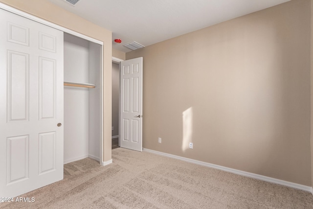 unfurnished bedroom featuring a closet and light colored carpet