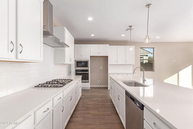 kitchen featuring pendant lighting, wall chimney range hood, sink, dark hardwood / wood-style flooring, and stainless steel appliances