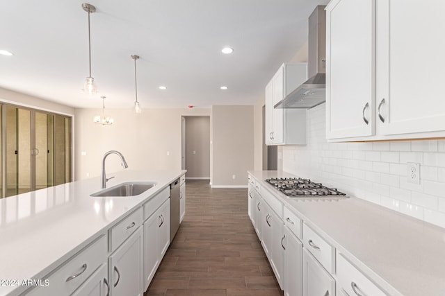 kitchen with sink, wall chimney range hood, dark hardwood / wood-style floors, pendant lighting, and white cabinets