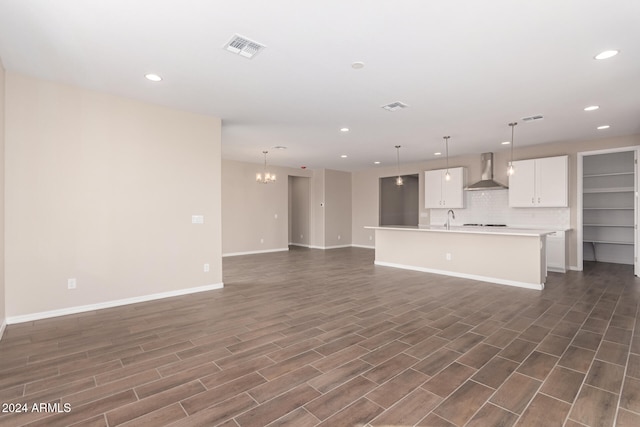 unfurnished living room featuring sink, dark wood-type flooring, and a notable chandelier