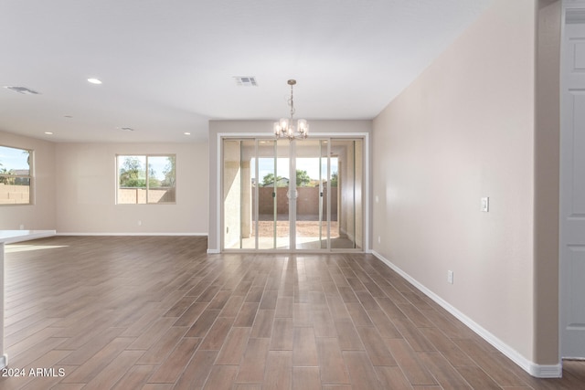 unfurnished room with a chandelier and dark hardwood / wood-style floors