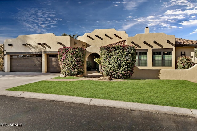 pueblo-style home featuring a front yard and a garage