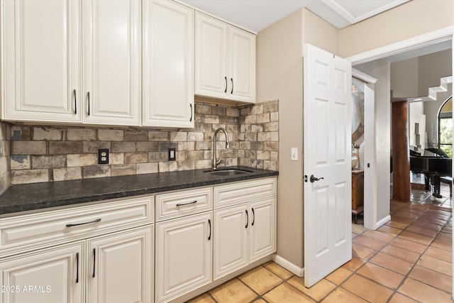 kitchen featuring tasteful backsplash, sink, white cabinetry, and light tile patterned flooring