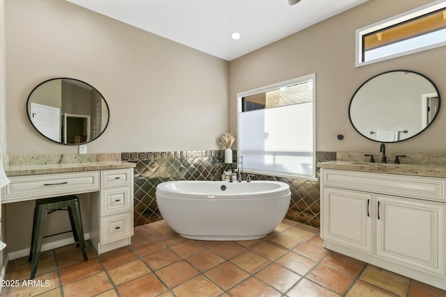 bathroom with tile patterned floors, tile walls, a tub to relax in, and vanity