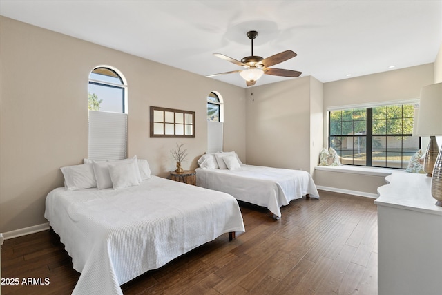 bedroom featuring ceiling fan, dark hardwood / wood-style flooring, and multiple windows