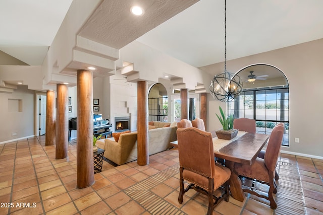 tiled dining room with ceiling fan and a fireplace