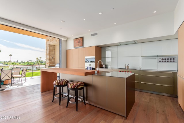 6311 E Phoenician Blvd Unit 18, Scottsdale, AZ 85251 - kitchen with a sink, modern cabinets, a breakfast bar area, hardwood / wood-style flooring, and an island with sink