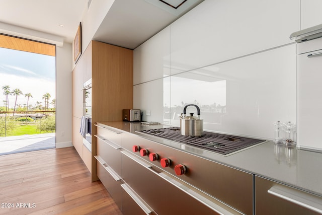 kitchen with light hardwood / wood-style floors, white cabinetry, and stainless steel gas cooktop