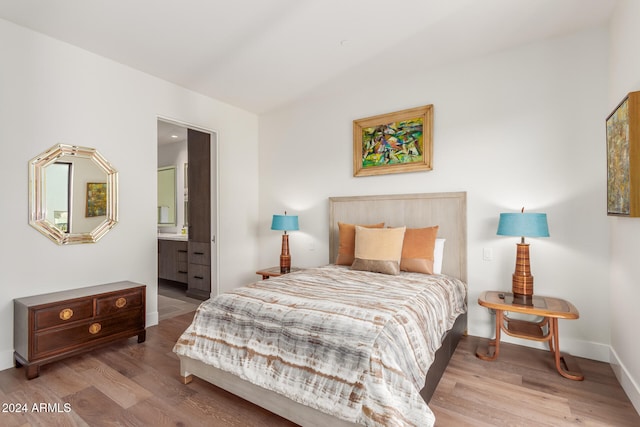 bedroom with ensuite bathroom and light hardwood / wood-style flooring