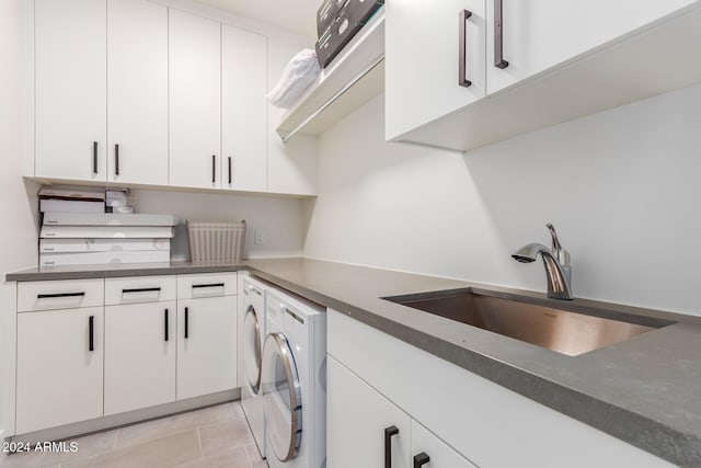 kitchen with white cabinets, light tile patterned flooring, washing machine and dryer, and sink