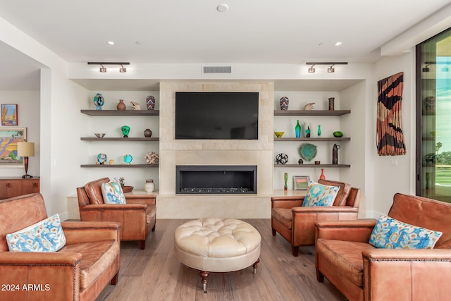 living room with hardwood / wood-style floors, a large fireplace, and track lighting