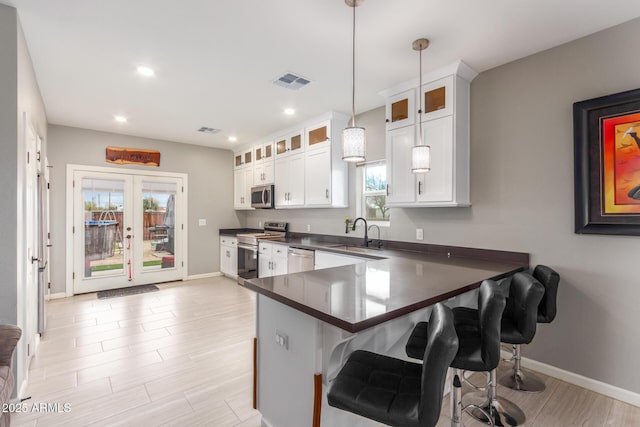 kitchen with visible vents, dark countertops, appliances with stainless steel finishes, a kitchen bar, and a sink