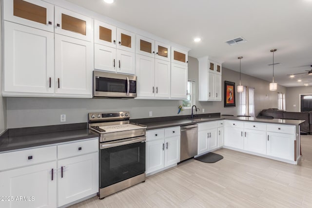 kitchen with stainless steel appliances, a peninsula, a sink, visible vents, and dark countertops