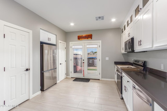 kitchen featuring visible vents, white cabinets, dark countertops, stainless steel appliances, and french doors