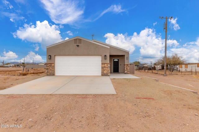 view of front facade with a garage, driveway, stone siding, and stucco siding