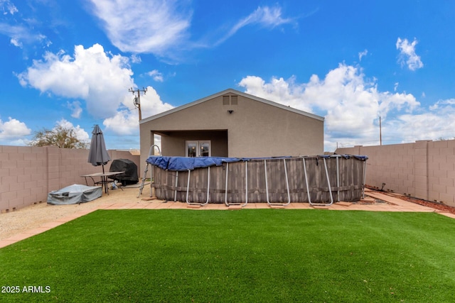 back of house featuring a yard, a fenced backyard, and stucco siding