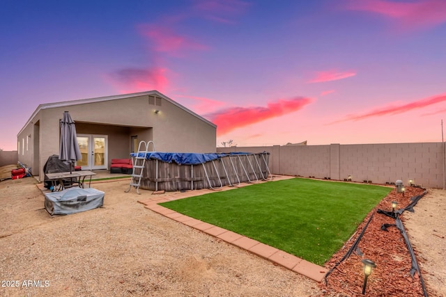 view of yard featuring french doors, a patio area, a fenced backyard, and a fenced in pool