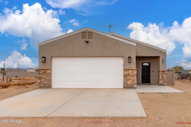 view of front facade with driveway, stone siding, a garage, and stucco siding