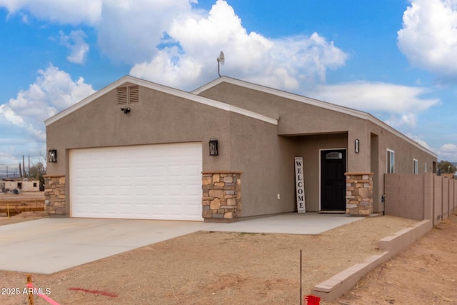 view of front of house with driveway, stone siding, and stucco siding