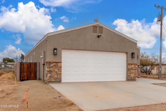 view of property exterior featuring a garage, stone siding, fence, and stucco siding