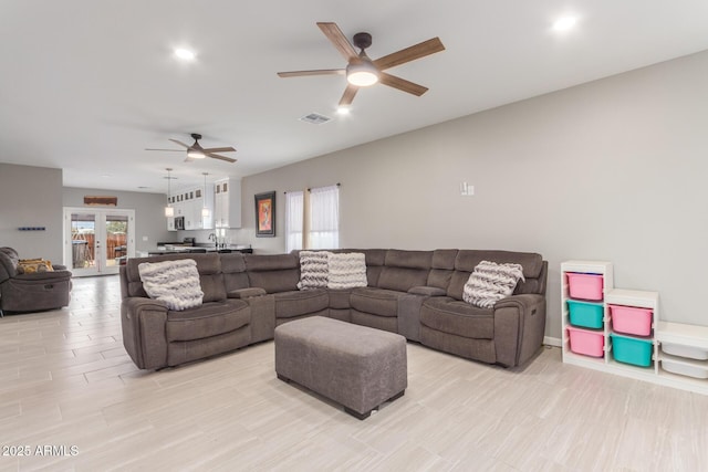 living area featuring french doors, visible vents, and a ceiling fan