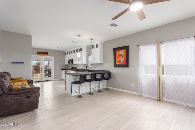 kitchen featuring stainless steel appliances, visible vents, open floor plan, dark countertops, and a kitchen bar