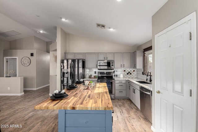 kitchen featuring visible vents, butcher block counters, appliances with stainless steel finishes, gray cabinets, and a sink