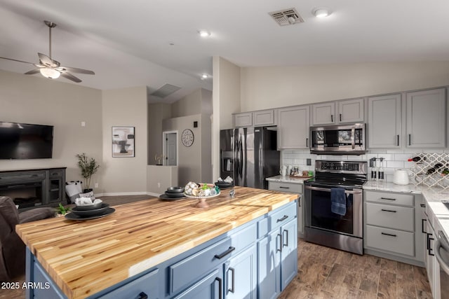 kitchen featuring stainless steel appliances, lofted ceiling, visible vents, open floor plan, and butcher block countertops