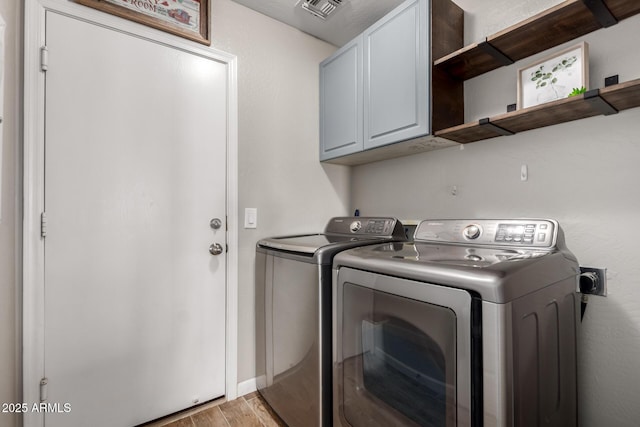 clothes washing area featuring visible vents, light wood-type flooring, independent washer and dryer, and cabinet space