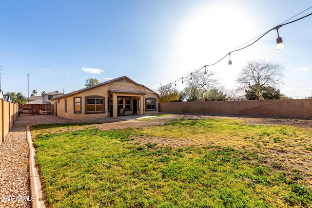 rear view of property featuring a patio area, a fenced backyard, a lawn, and stucco siding