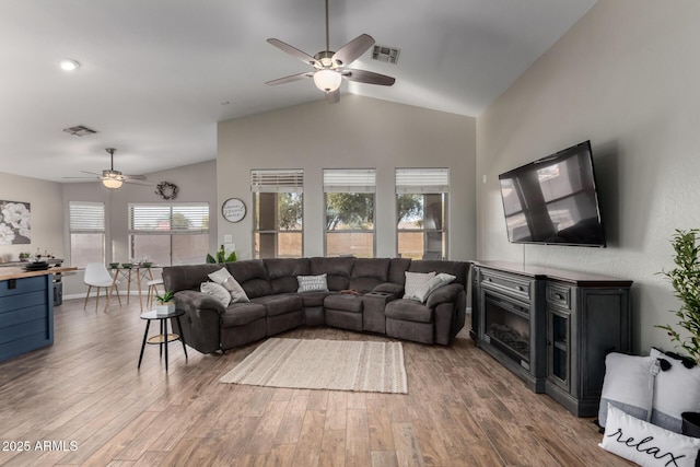 living room with ceiling fan, visible vents, vaulted ceiling, and wood finished floors