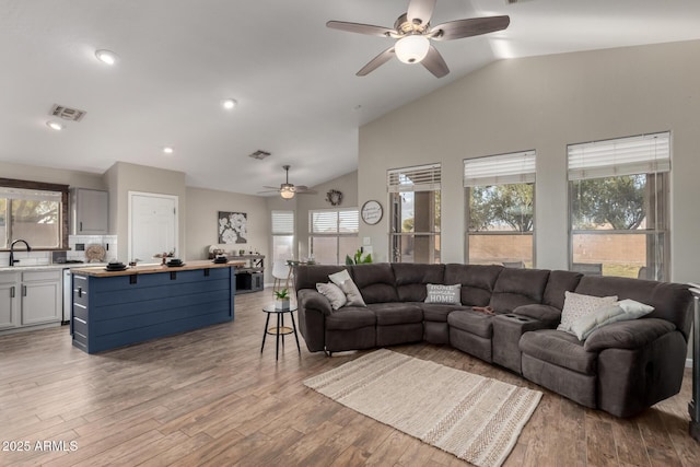 living area featuring lofted ceiling, light wood finished floors, visible vents, and recessed lighting