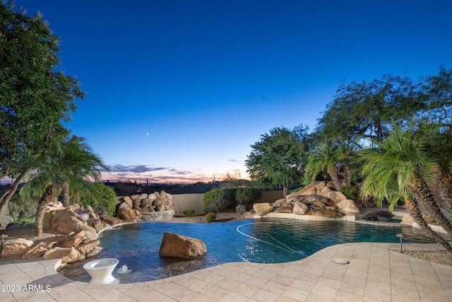 pool at dusk featuring a patio